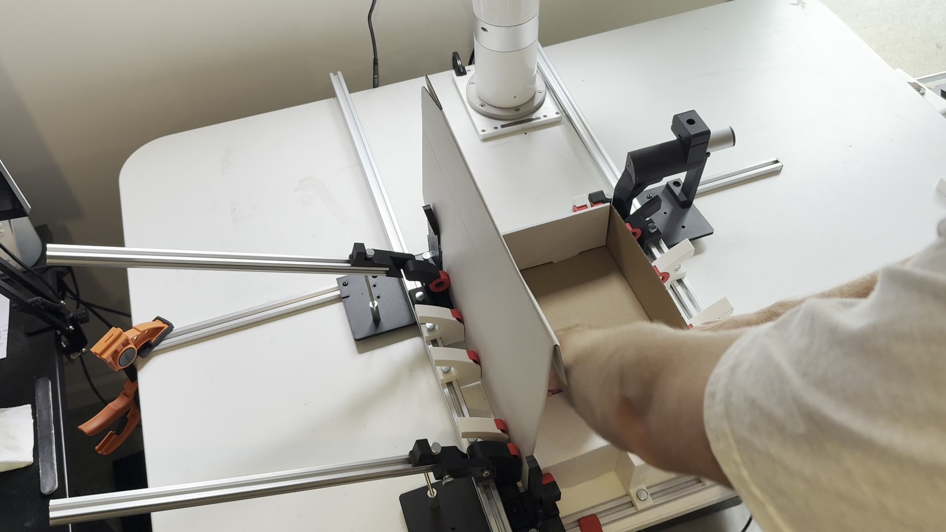 A hinged-lid corrugated mailer being formed in the actual fixture